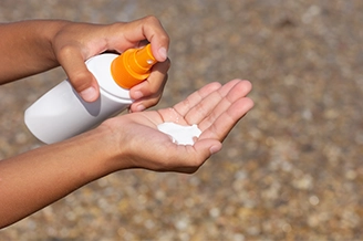 Person applying sunscreen to protect skin from sun damage and harmful UV rays